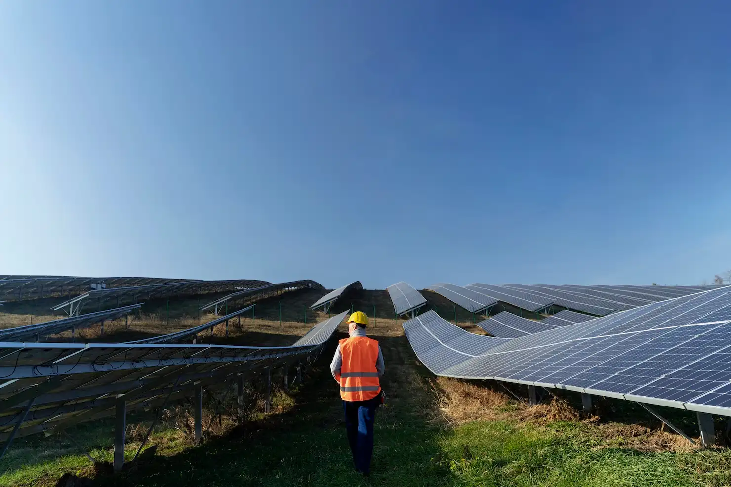 Técnico caminhando entre fileiras de painéis solares de uma usina